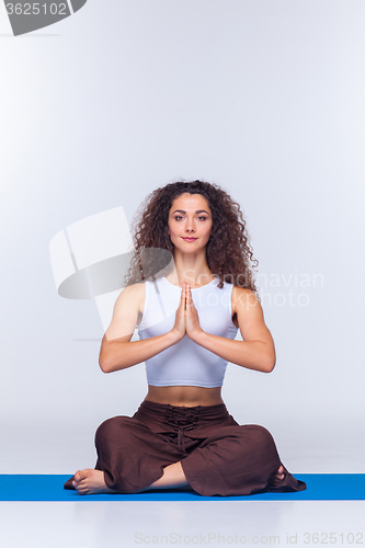 Image of Studio shot of a young fit woman doing yoga exercises.