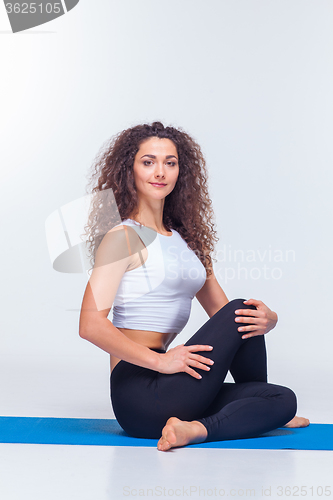 Image of Studio shot of a young fit woman doing yoga exercises.