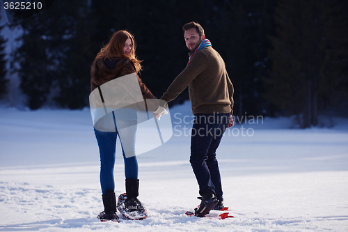 Image of couple having fun and walking in snow shoes