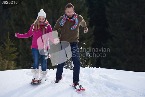 Image of couple having fun and walking in snow shoes