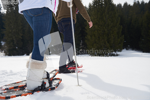 Image of couple having fun and walking in snow shoes