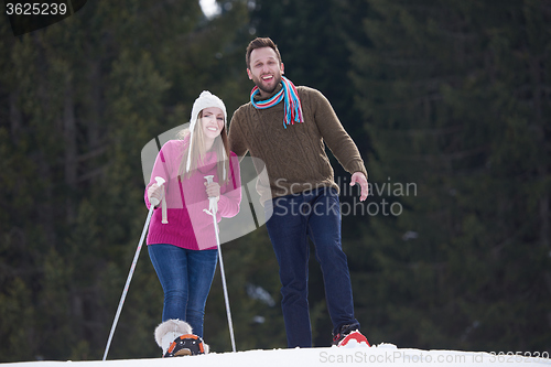 Image of couple having fun and walking in snow shoes