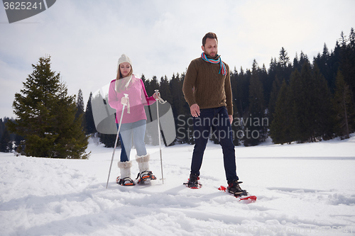 Image of couple having fun and walking in snow shoes