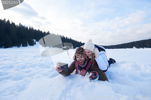 Image of romantic couple have fun in fresh snow and taking selfie