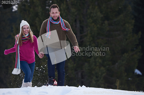 Image of couple having fun and walking in snow shoes