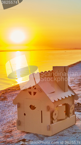 Image of Toy house made of corrugated cardboard in the sea coast at sunset.