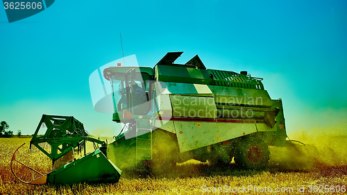 Image of Harvester combine harvesting wheat on summer day.