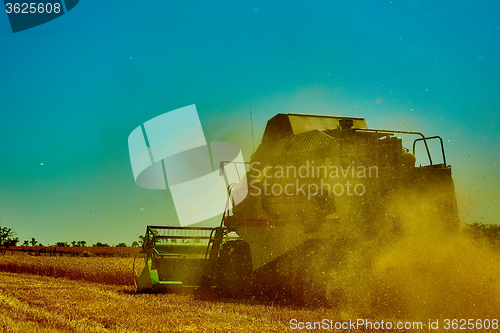 Image of Harvester combine harvesting wheat on summer day.