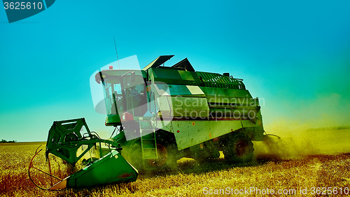 Image of Harvester combine harvesting wheat on summer day.