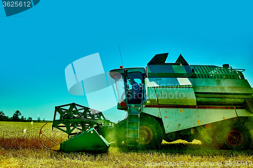 Image of Harvester combine harvesting wheat on summer day.