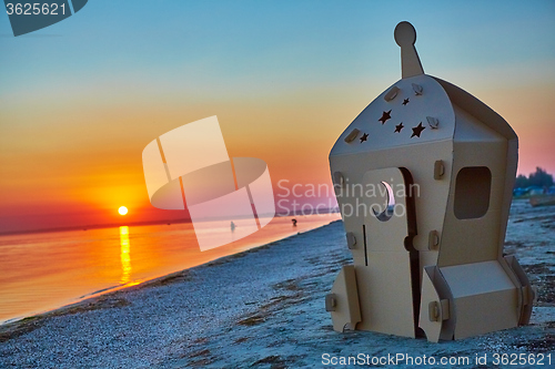 Image of Cardboard toy spaceship at sea coast and sunset.