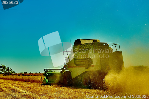 Image of Harvester combine harvesting wheat on summer day.