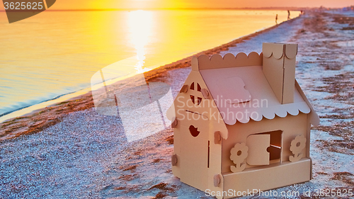 Image of Toy house made of corrugated cardboard in the sea coast at sunset.