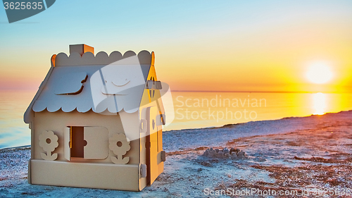 Image of Toy house made of corrugated cardboard in the sea coast at sunset.