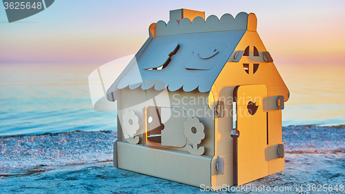 Image of Toy house made of corrugated cardboard in the sea coast at sunset.