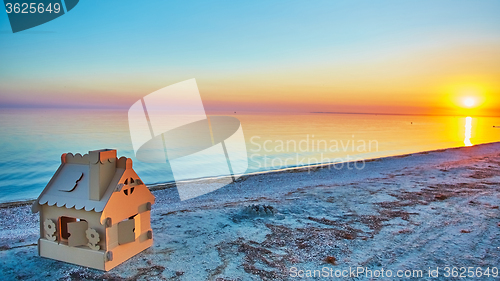 Image of Toy house made of corrugated cardboard in the sea coast at sunset.