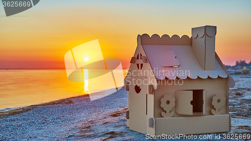 Image of Toy house made of corrugated cardboard in the sea coast at sunset.