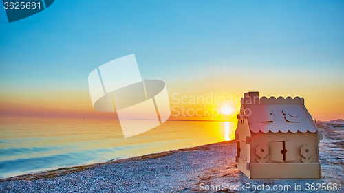 Image of Toy house made of corrugated cardboard in the sea coast at sunset.