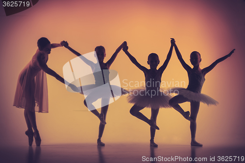 Image of Three little ballerinas dancing with personal ballet teacher in dance studio