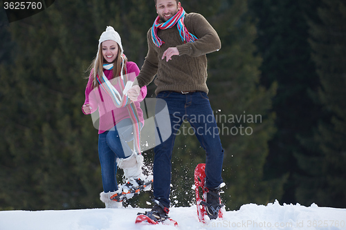 Image of couple having fun and walking in snow shoes