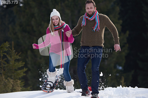 Image of couple having fun and walking in snow shoes