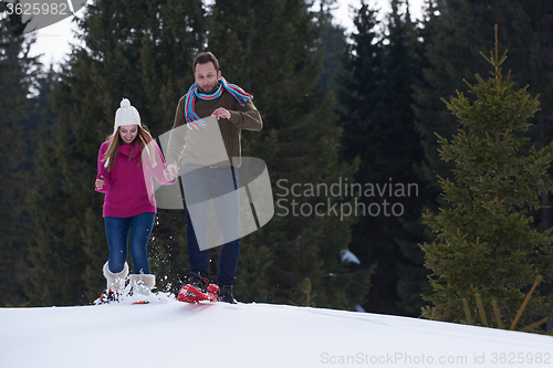 Image of couple having fun and walking in snow shoes