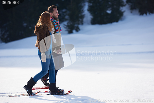 Image of couple having fun and walking in snow shoes