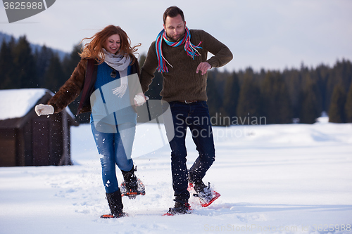 Image of couple having fun and walking in snow shoes