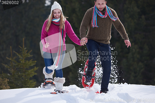 Image of couple having fun and walking in snow shoes