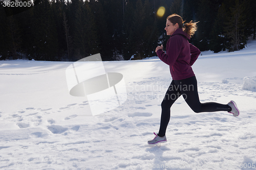 Image of yougn woman jogging outdoor on snow in forest