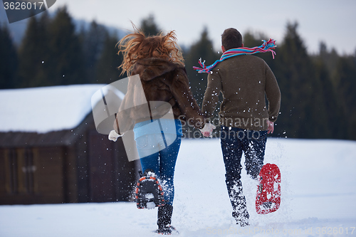 Image of couple having fun and walking in snow shoes