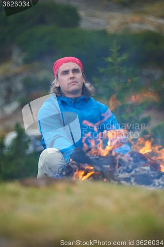 Image of hiking man prepare tasty sausages on campfire