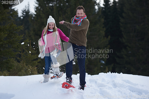 Image of couple having fun and walking in snow shoes