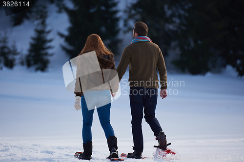 Image of couple having fun and walking in snow shoes