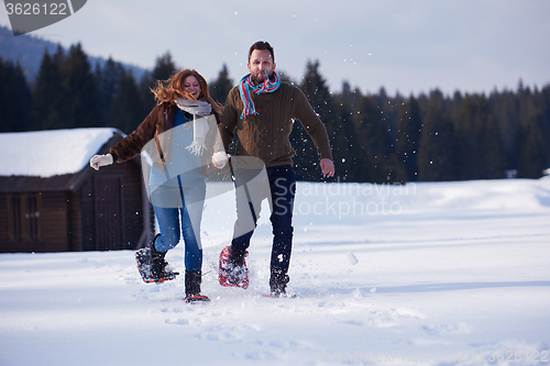 Image of couple having fun and walking in snow shoes