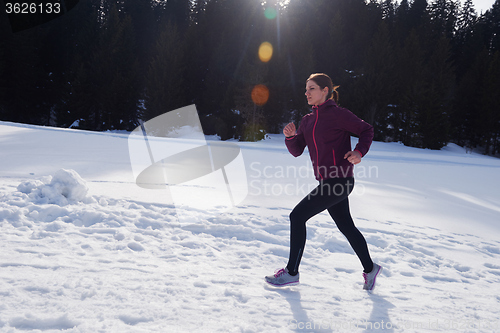 Image of yougn woman jogging outdoor on snow in forest