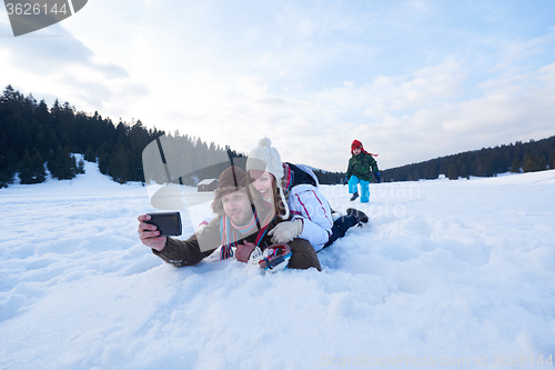 Image of romantic couple have fun in fresh snow and taking selfie