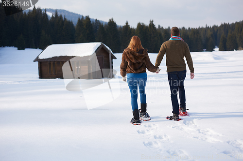 Image of couple having fun and walking in snow shoes