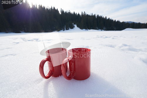 Image of two red coups of hot tea drink in snow  at winter