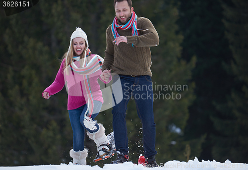 Image of couple having fun and walking in snow shoes