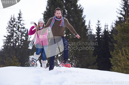 Image of couple having fun and walking in snow shoes