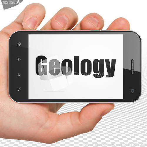 Image of Studying concept: Hand Holding Smartphone with Geology on display