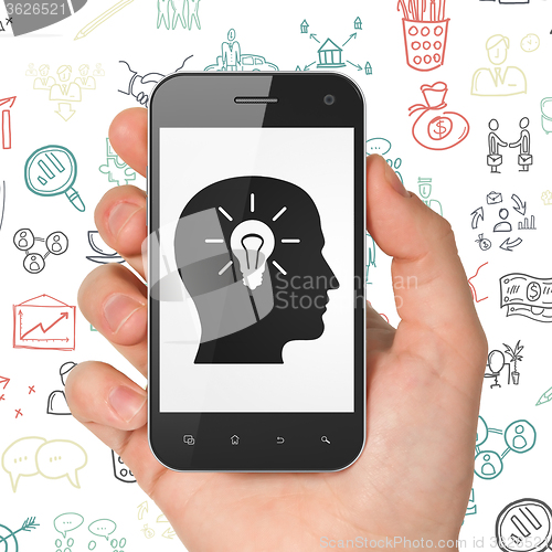Image of Business concept: Hand Holding Smartphone with Head With Light Bulb on display