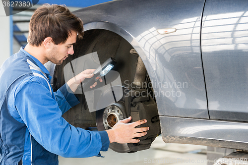 Image of Mechanic Examining Brake Disc Of Car In Garage