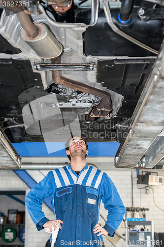 Image of Mechanic Examining the state of an exhaust system Under The Car 