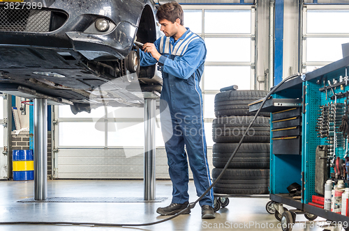 Image of Mechanic Repairing Car On Hydraulic Lift