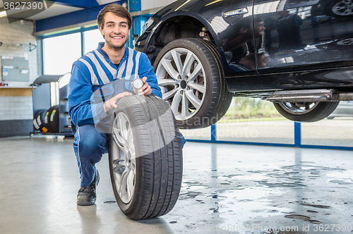 Image of Mechanic Pressing Gauge Into Tire Tread In Garage