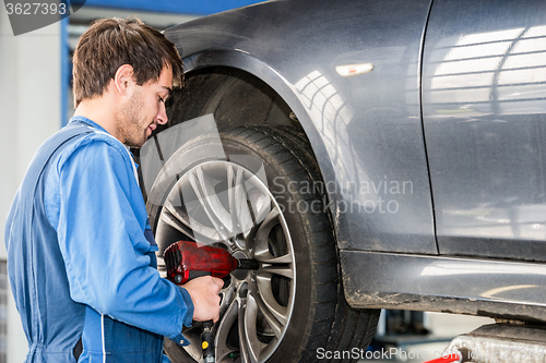 Image of Mechanic Changing Wheel On Car With Pneumatic Wrench