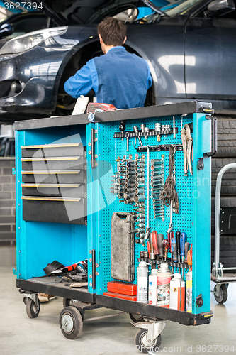 Image of Tool Cart With Male Mechanic Repairing Car