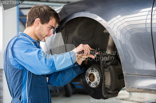 Image of Car Mechanic Examining Brake Disc With Caliper